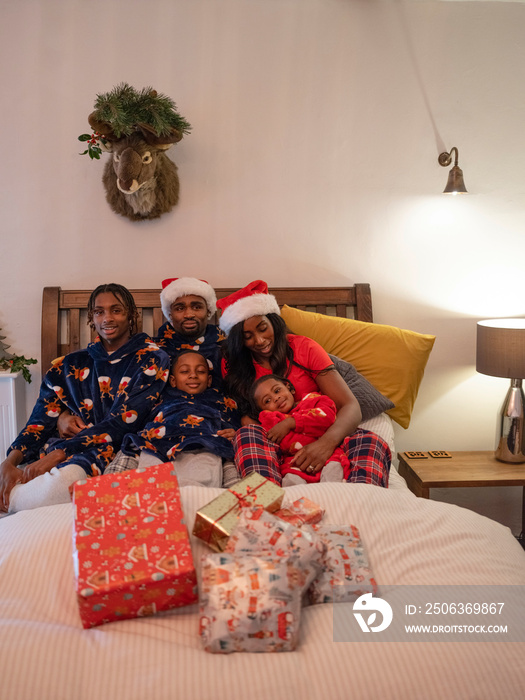 Family portrait with Christmas presents in bed at home