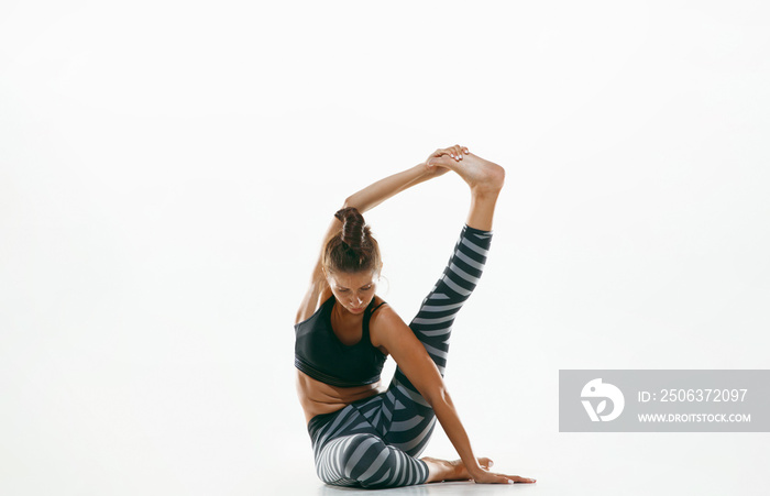 Sporty young woman doing yoga practice isolated on white studio background. Fit flexible female mode