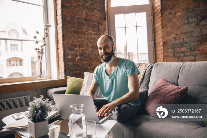 Text typing. Young man doing yoga at home while being quarantine and freelance online working. Remot