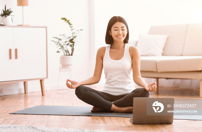 Millennial woman meditating with trainer online on laptop