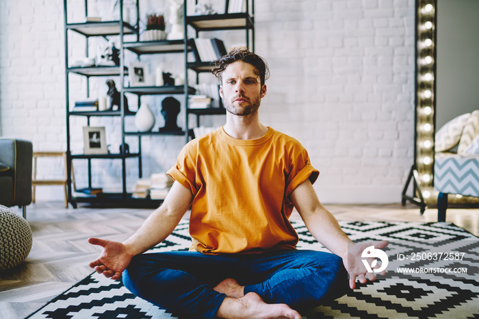 Young man sitting in easy seat yoga pose in living room