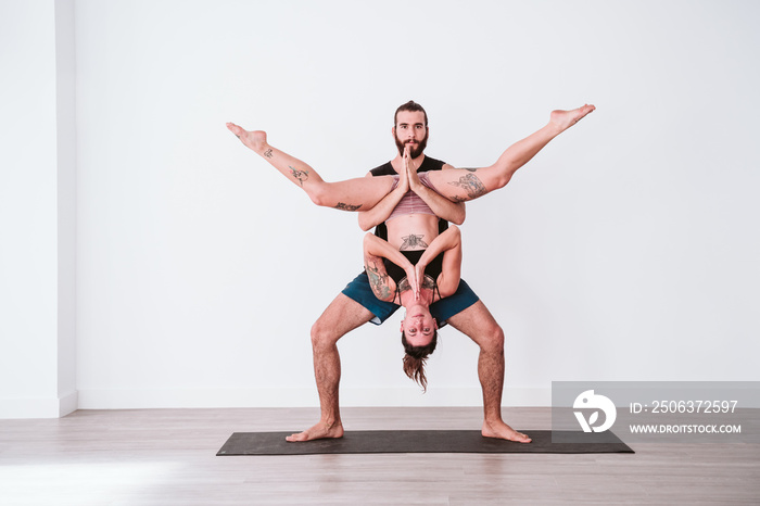 young couple Couple practicing acro yoga in white studio or gym. Healthy lifestyle