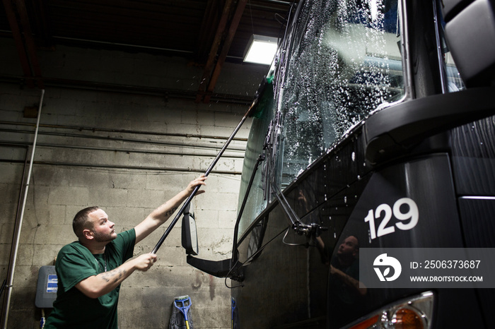 Man washing windshield of tour bus