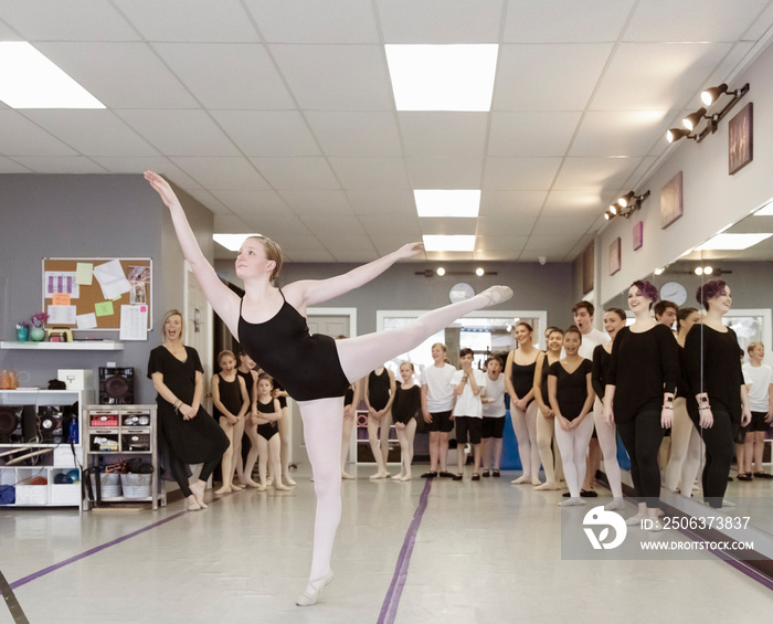 Instructors with students looking at ballerina performing in ballet studio