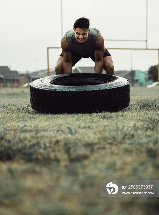 Muscular athlete doing a tire flip workout