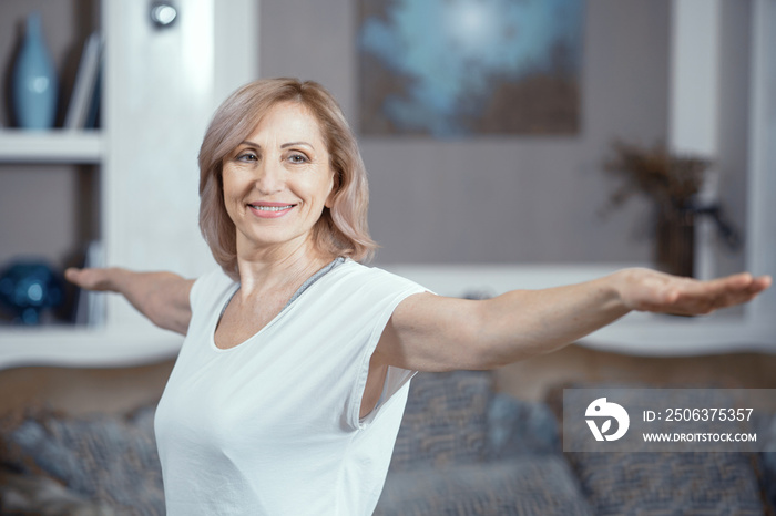 一位50岁的女士在家的客厅练习瑜伽。