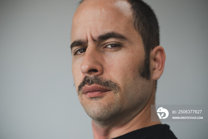 White man with a prominent mustache looking straight at the camera against a seamless background