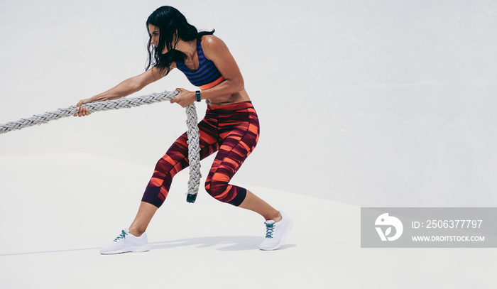 Fitness woman doing workout using a battle rope