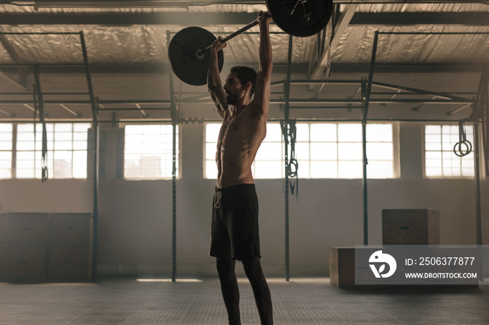 Muscular man exercising with barbell