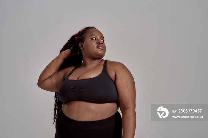 Your body, your rules. Plump, plus size african american woman in black sportswear looking aside whi