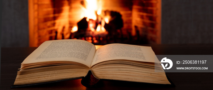 Book open, fireplace burning firewood background. Reading and relax near the fire