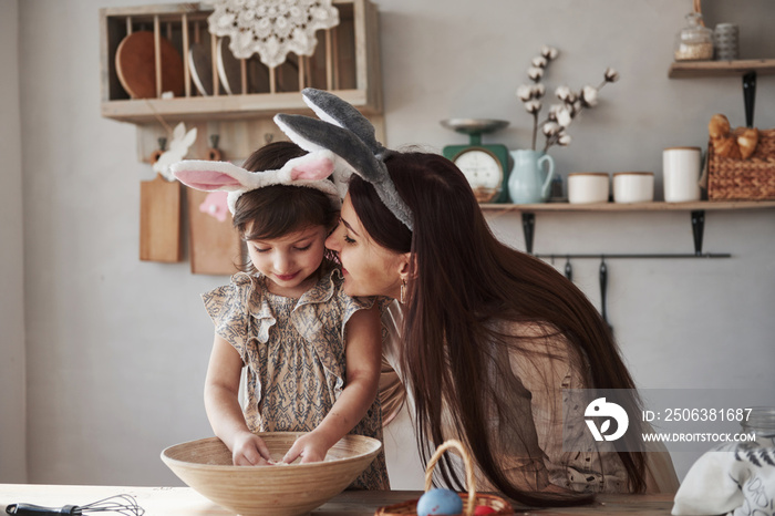 Family bonding. Mother and daughter in bunny ears at easter time have some fun in the kitchen at day