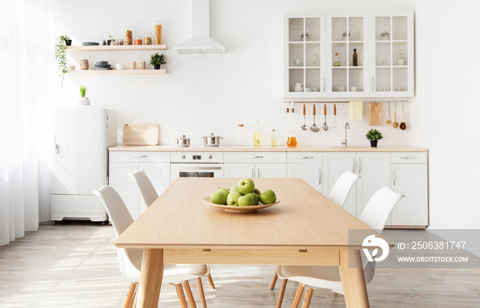 舒适的现代厨房内部，配有浅色地板和家具，木制乡村餐桌。浅色空房间b