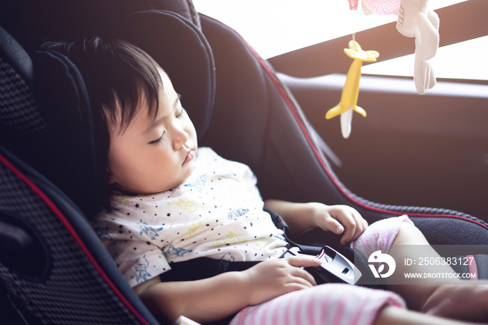 亚洲可爱的蹒跚学步的小女孩在车里睡在儿童安全座椅加高座椅婴儿座椅上