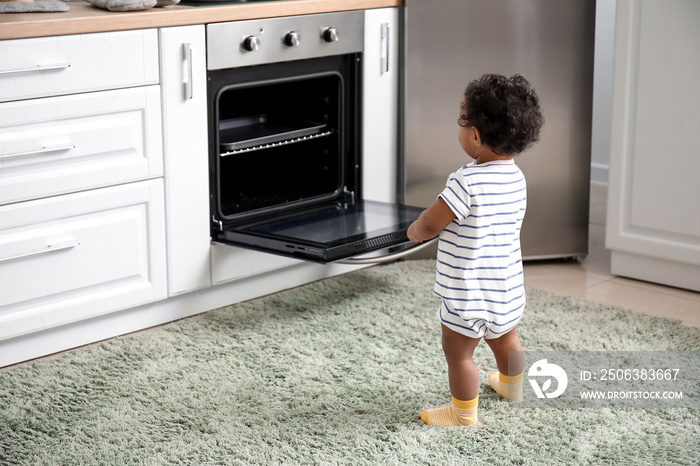 厨房火炉旁的非洲裔小婴儿。孩子处于危险之中