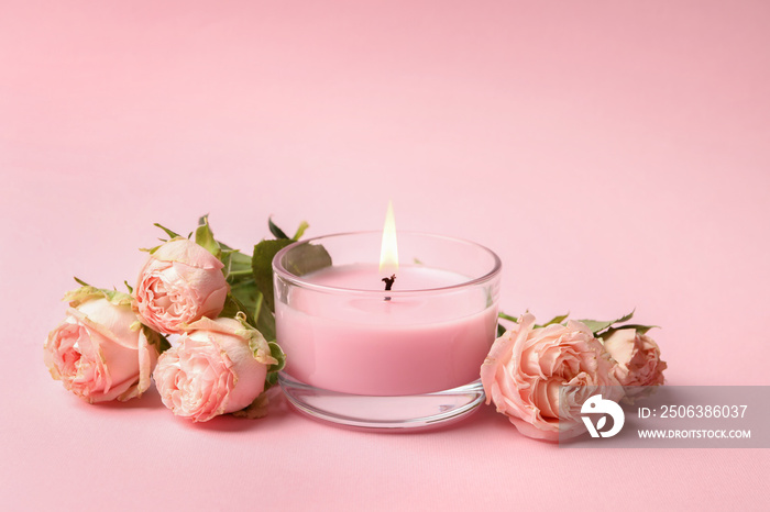 Scented candle and roses on pink background