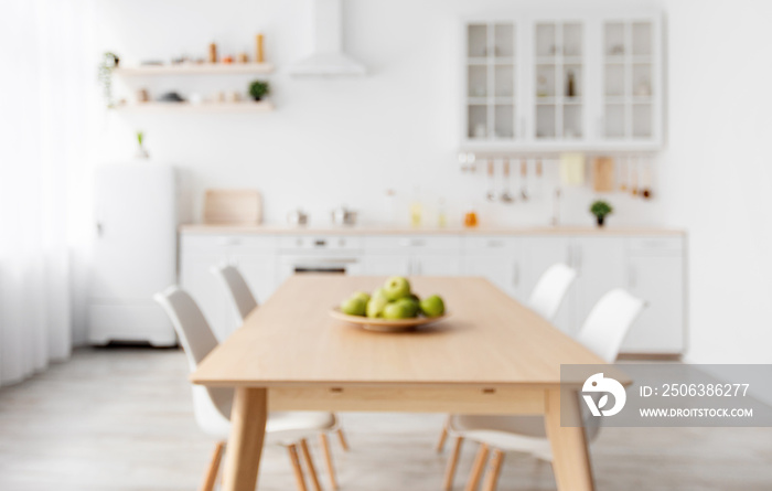 Blurred photo of scandinavian classic kitchen with wooden and white details. Dining table and light 