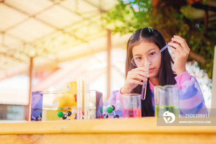 Asian teenage girl in elementary science class doing chemical experiment test try to drop color wate