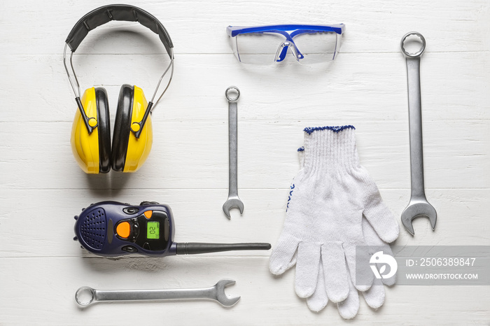 Safety equipment with builders tools and radio transmitter on white wooden background