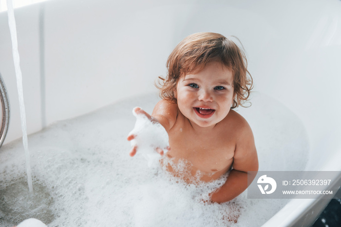 Cute little girl washing in the bat at home. Top view