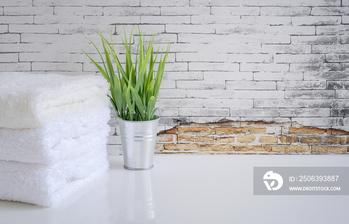 白色桌子上的白毛巾和室内植物，有旧砖墙