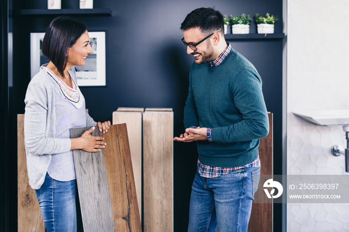 Middle age man choosing ceramic tiles and utensils for his home bathroom and female seller helps him