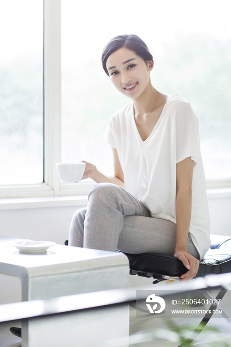 快乐的年轻女子在咖啡店喝咖啡