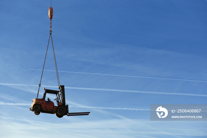 A forklift truck being transported on a platform by a crane