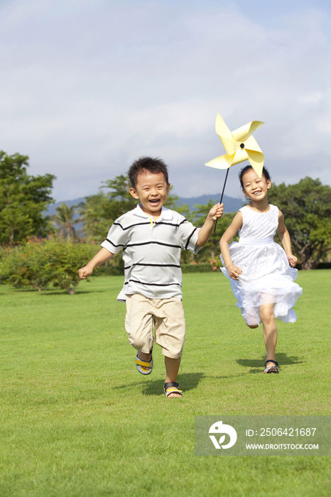 儿童拿着风车在草地上奔跑