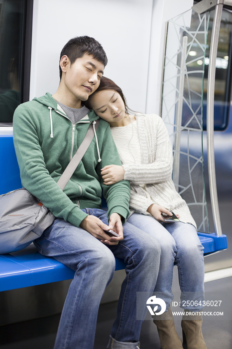 疲倦的年轻情侣坐在地铁里