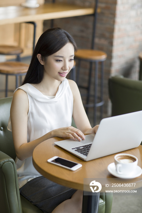 年轻女士在咖啡厅使用笔记本电脑工作