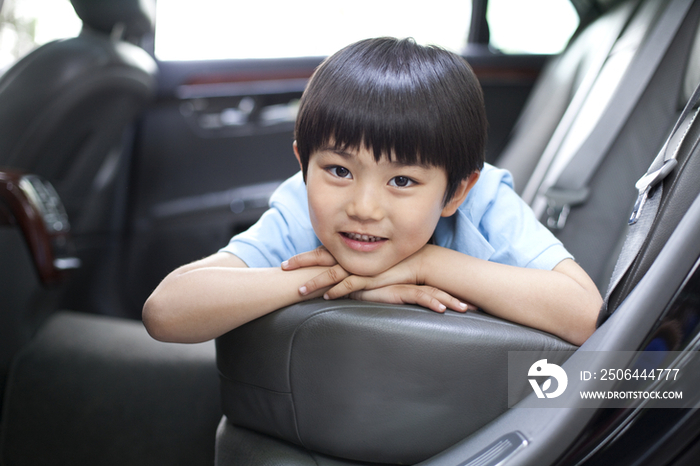 快乐的小男孩趴在汽车后座上
