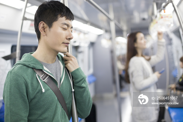 疲倦的年轻男子站在地铁里