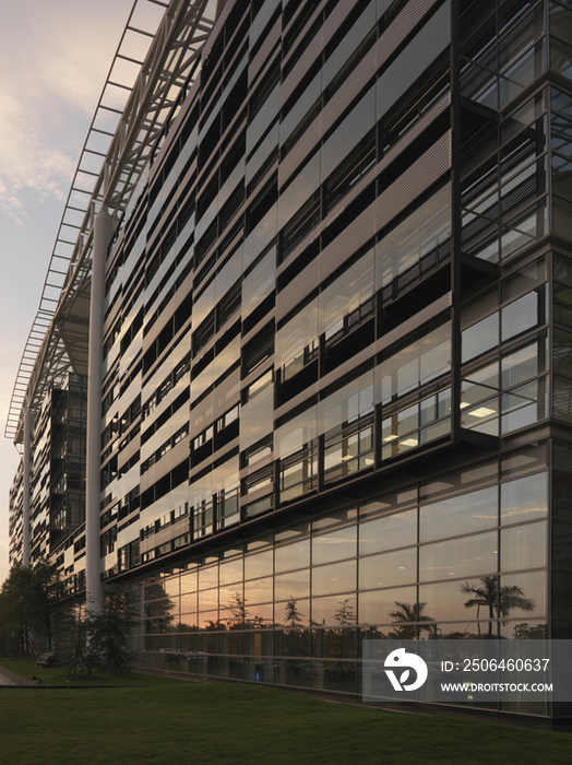 Low angle view of modern corporate building and lawn against the sky at dusk