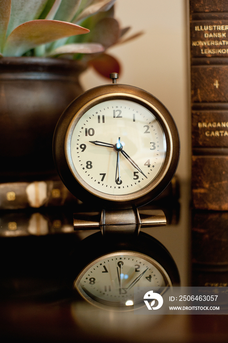 Close-up of a clock with reflection on table at home