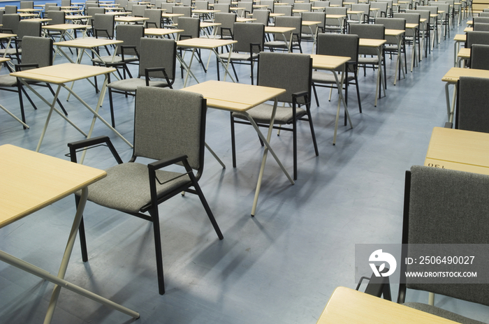 The main hall of a modern secondary school set out for exams with rows of desks and chairs