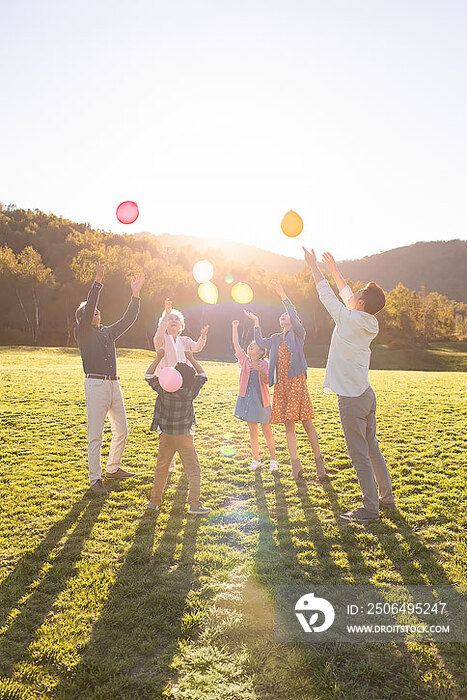 快乐的的六口之家在草地上玩气球