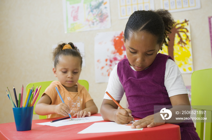 Jeunes enfants en classe de maternelle dessinant