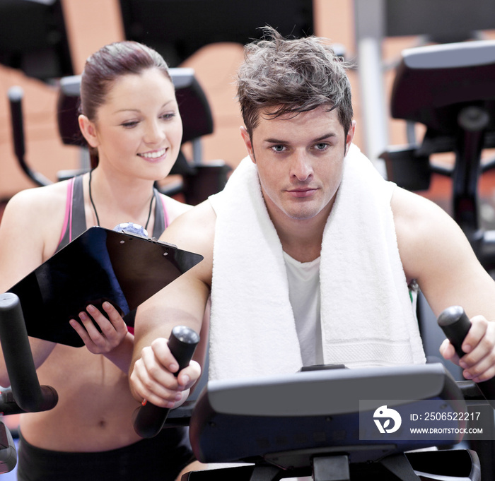 Smart female coach taking notes while her pupil is pedaling