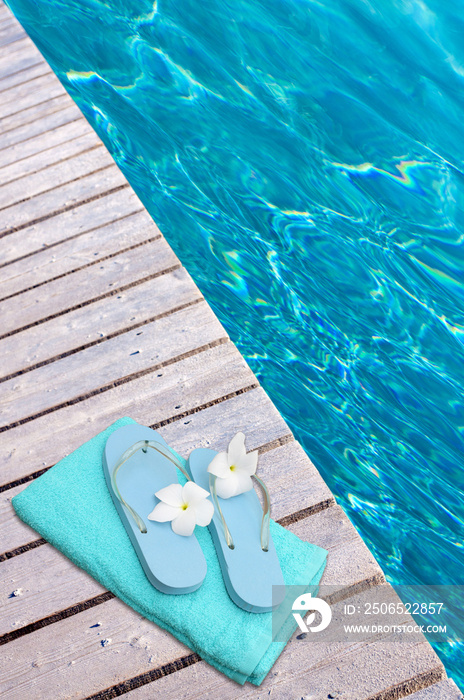 serviette et tongs sur margelle de piscine