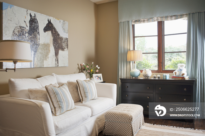 Sofa set with random objects on end table against window in living room at house