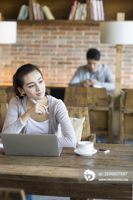 年轻女子在咖啡馆使用笔记本电脑