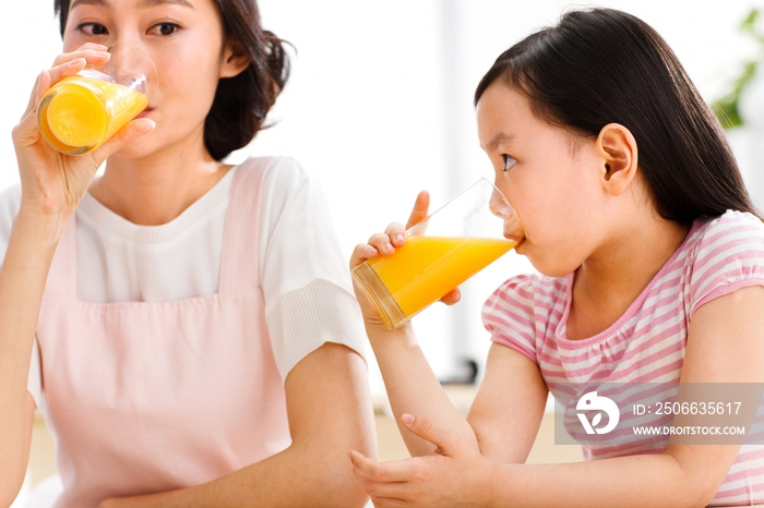 母亲和女孩在喝果汁