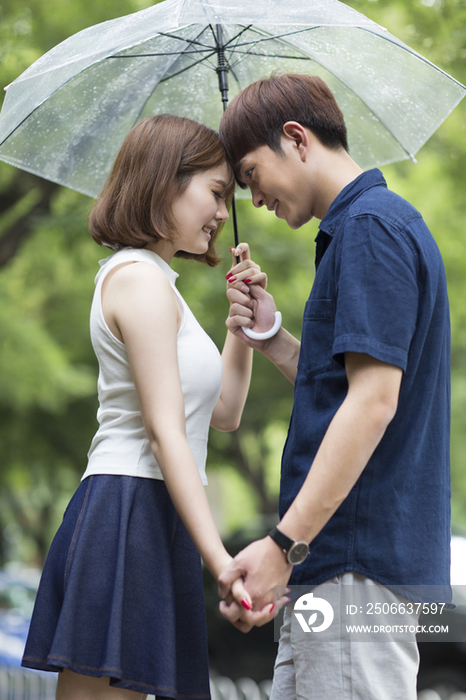 年轻情侣打着雨伞