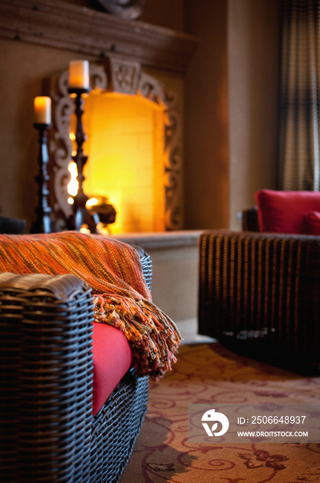 Cropped wicker armchair against lit fireplace in living room at home; Scottsdale; USA