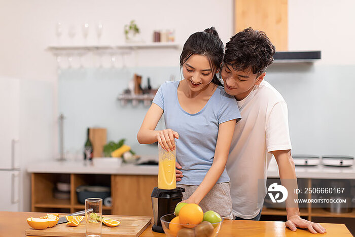 快乐的年轻夫妇在厨房使用榨汁机