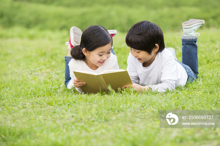 小男孩和小女孩在草地上读书