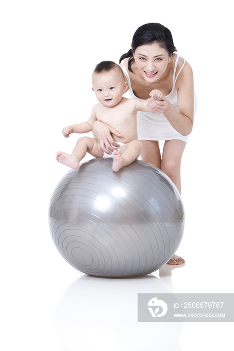 母亲指导婴儿在健身球上玩
