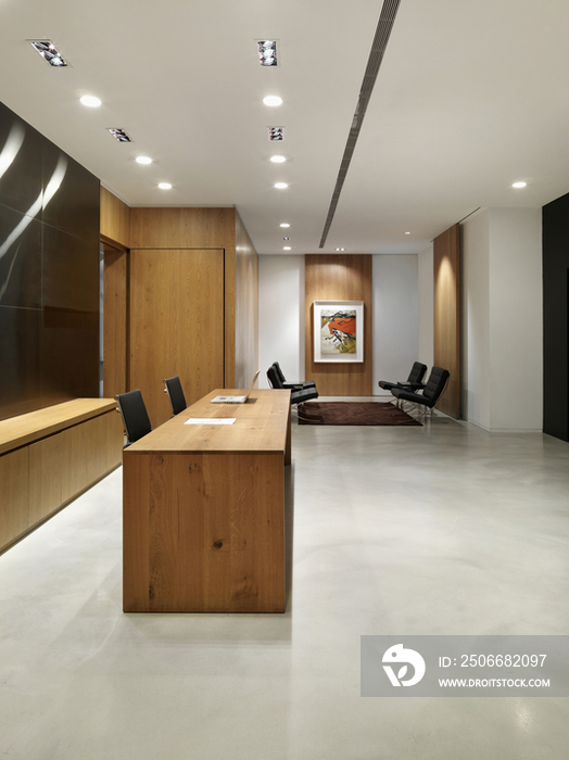 Wooden reception desk with chairs in office