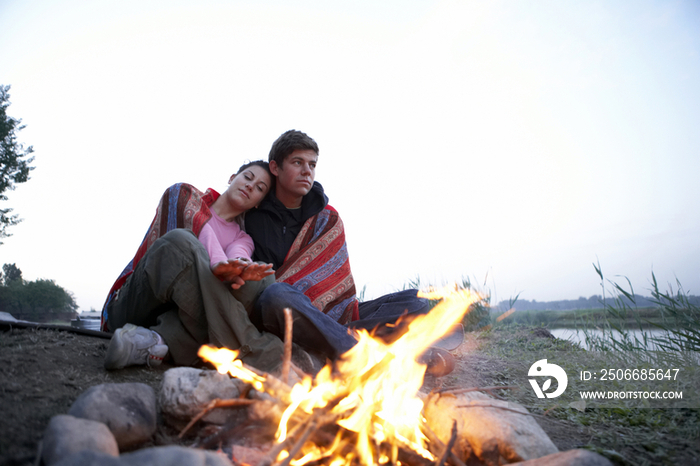 年轻情侣坐在篝火旁